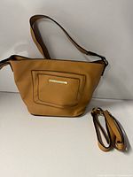 Front view of tan Nicole Lee handbag showing shoulder strap, front pocket and extra detachable strap