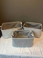 Three grey fabric storage baskets displayed
