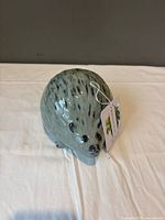 Front three-quarter view of green hedgehog planter with tag attached