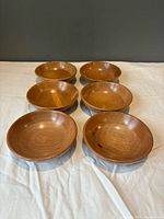 Six matching wooden salad bowls arranged in two rows