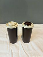 Front view of both brown Tupperware shakers with tops on