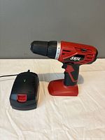 Drill without battery beside charger on tabletop
