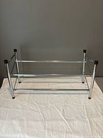 front view of chrome two-tier shoe rack on cloth backdrop