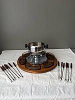 full fondue set laid out: pot on stand, tray, glass dishes, forks
