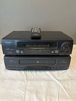 Stacked Sharp and GE VCRs with remote on top