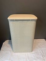 Front view of cream woven laundry hamper closed