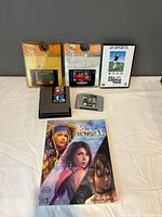 All items laid out: NES, N64, Genesis cartridges, sealed Genesis packs, strategy guide front