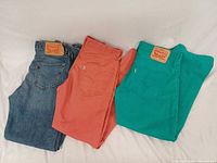 Three pairs of Levi's jeans in blue, coral, teal
