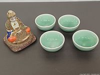 Front view of Buddha statue and four celadon bowls