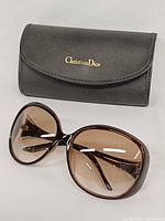 Front view of oversized Dior sunglasses with case behind