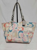 Front view of Coach multicolor optic print tote handbag with straps and hangtag visible
