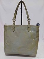 Front view of Coach patent leather tote showing embossed C pattern and straps