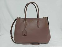 Front view of Kate Spade Eva satchel showing logo, handles, detachable strap, luggage tag