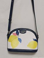 Front view of handbag showing lemon print, shape and strap