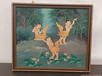 Front view of framed Thai painting depicting three kinnari figures