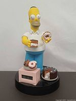 Front view of Homer Simpson talking alarm clock showing digital display, donut and cake accessories