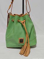 Full view of green patent leather bucket bag with drawstring and tassels
