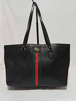 Front view showing black leather, green-red stripe, GG logo, twin handles