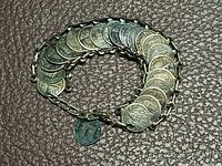 Full view of coin bracelet coiled to show linked coins