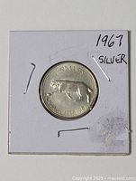 Full view of obverse and reverse sides of the 1967 silver quarter in flip
