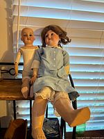 Both dolls seated showing size difference, dress, bodies