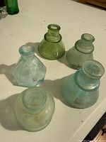 Group of five antique glass ink bottles showing shapes and colours
