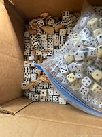 Open box showing large quantity of loose six-sided dice with black pips