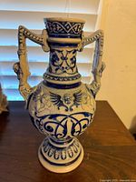 Front view showing full form, pedestal base, bulbous body, narrow neck, twin figural handles, cobalt decoration