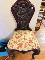 Full view of carved wooden chair with upholstered seat