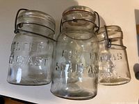 Front view of three Foster Sealfast glass canning jars showing embossed text and wire bails
