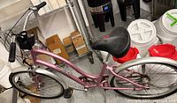 Side view of pink Electra Townie bicycle showing overall frame, wheels, handlebars and saddle