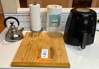 Group shot of all kitchen items: air fryer, tea kettle, cutting board, paper towel holder with roll