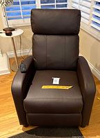 Front view of dark brown massage recliner showing seat, backrest and remote on arm