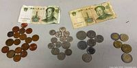 Overview of full lot: two Chinese 1 Yuan notes and four grouped piles of assorted foreign coins