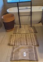 Group shot of hamper, three bath mats, black drying rack