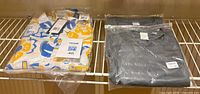 All three sealed shirts on shelf: UCLA graphic shirt and two gray performance T-shirts