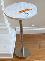 Full view of side table showing ceramic top and pedestal base