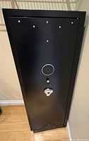 Front view of closed black gun safe showing biometric lock and keyed handle