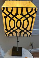 Full view of lamp showing patterned shade, metal stem, wood base