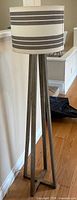 Full view of wood tripod floor lamp standing on hardwood floor