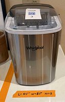 Front view of Whirlpool countertop ice maker showing stainless body and clear lid