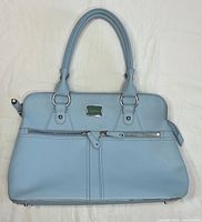 Front view of sky blue Modalu Pippa leather satchel showing handles, logo plate, front zippers