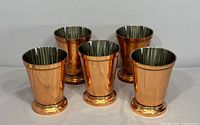 Front view of all five copper mint julep cups showing exterior finish and beaded detailing