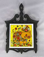 Front view showing pig and flowers tile within ornate cast iron frame