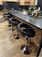 Four black swivel bar stools aligned at counter