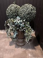 Cast iron planter holding artificial topiary