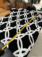 Full view of black and white electric blanket with tape measure for length
