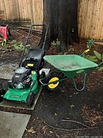 Lawn mower and wheelbarrow together outdoors