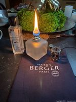 Lamp lit showing flame, refill bottle, snuffer cap and pouch