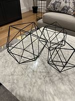 Three black metal geometric ornaments on marble table